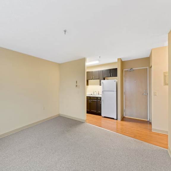 a spacious room with a kitchen in the background.