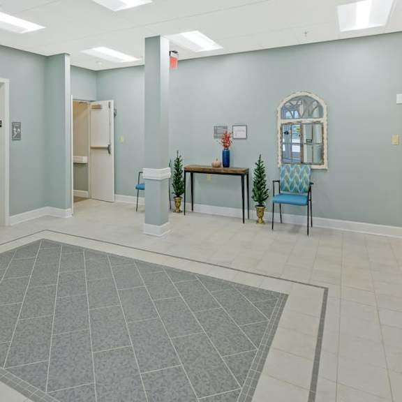a hallway with a grey rug and a blue chair.