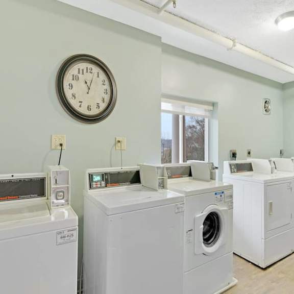a laundromat with a clock on the wall and washers and dryers.