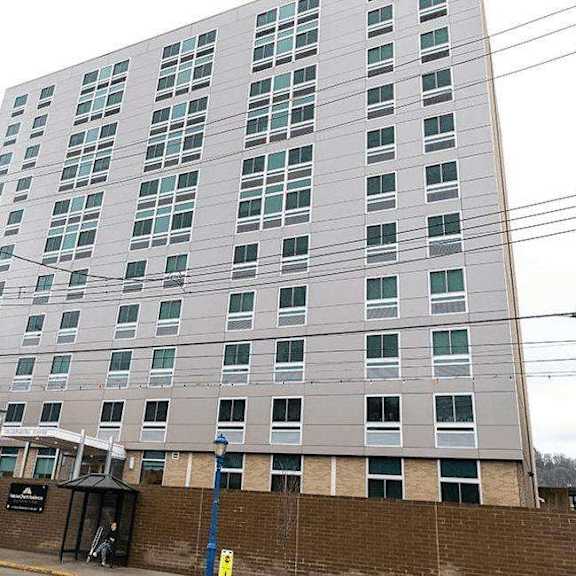 a tall building with a grey facade and a black awning.