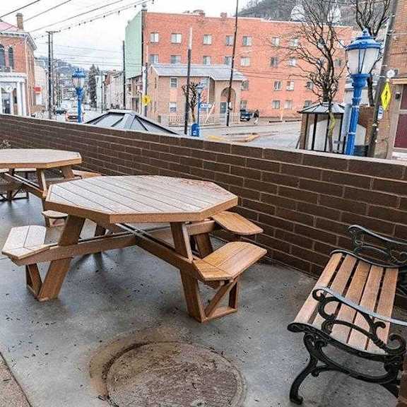 a wooden picnic table and bench are on a patio.