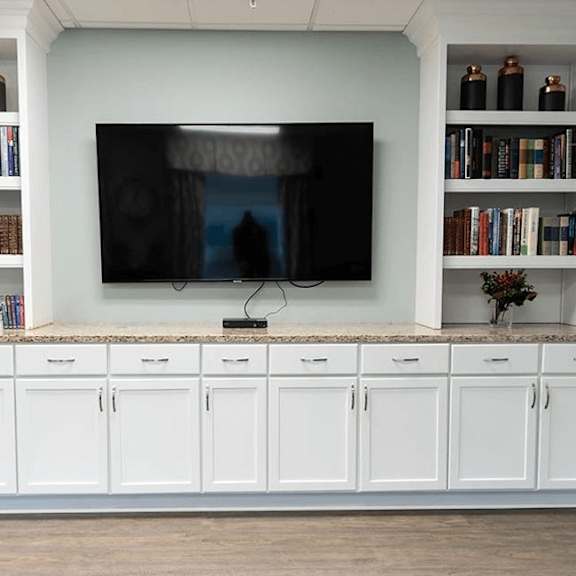 a black television is on a white shelf with books and vases.