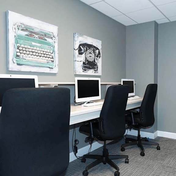 a room with a desk, two chairs, and a printer.