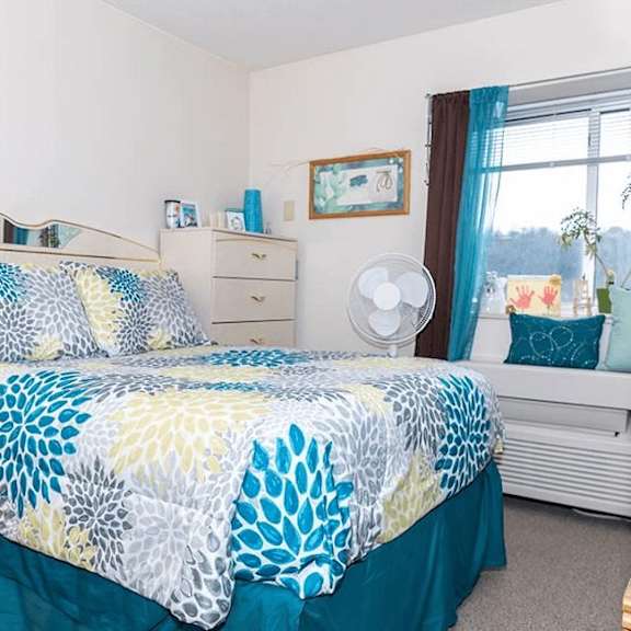 a bed with a blue and white comforter with a leaf pattern.