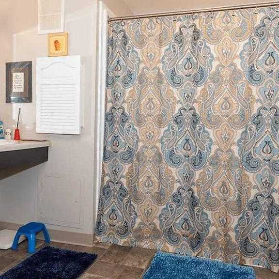 a bathroom with a blue and gold shower curtain.