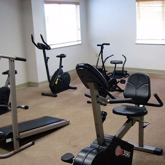 a room with exercise equipment including a treadmill, elliptical trainer, and stationary bike.