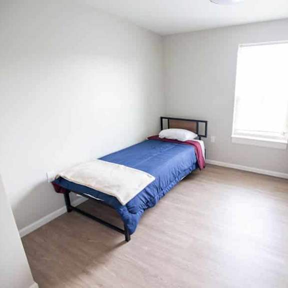 a bedroom with a bed, dresser, and window.