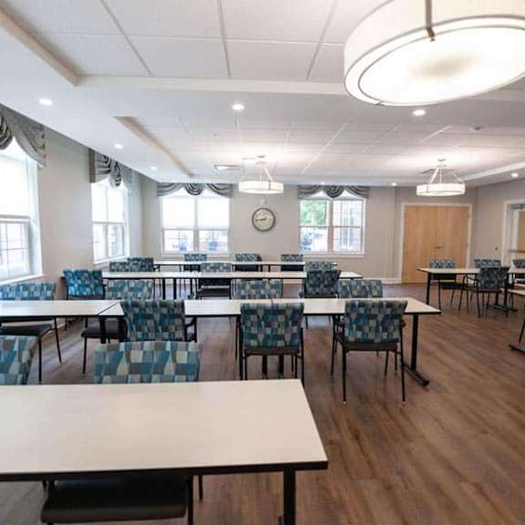 a room with tables and chairs and a clock on the wall.