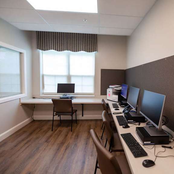 a room with a desk, chairs, and computer monitors.