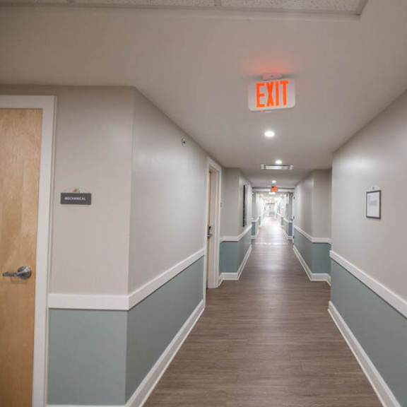 a long hallway with a red exit sign on the ceiling.