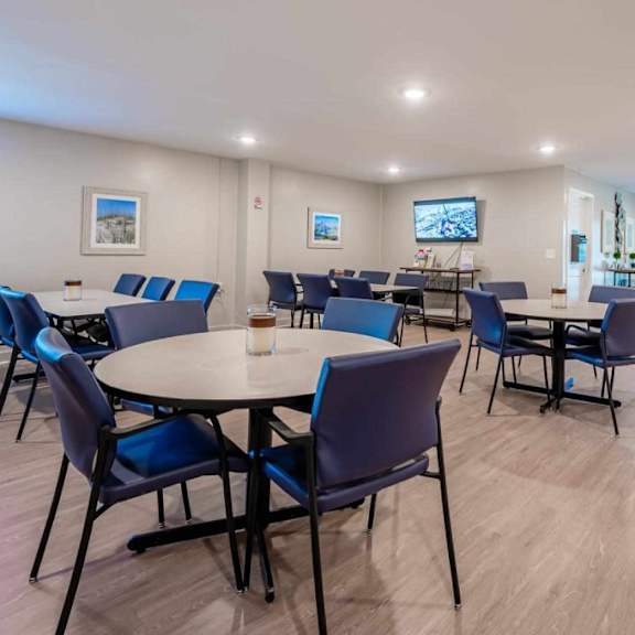 a room with tables and chairs is well lit with natural light.