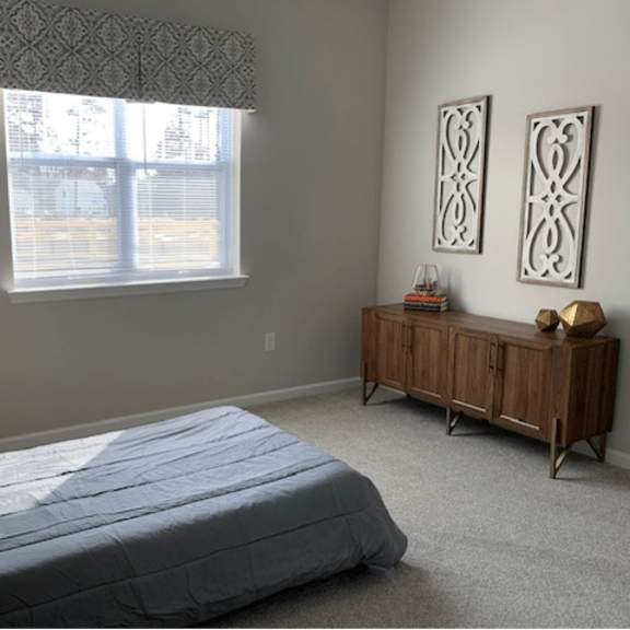 a bedroom with a bed, nightstand, and window.