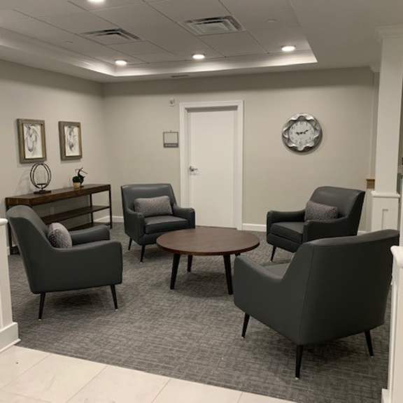 a room with grey chairs and a clock on the wall.