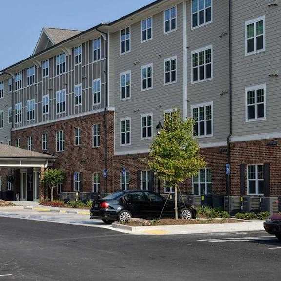 a large multi-story building with a parking lot in front.
