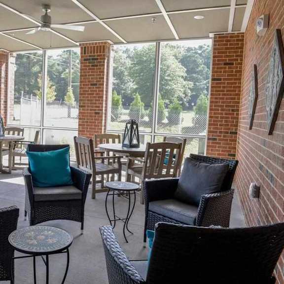 a patio with black wicker furniture and a brick wall.