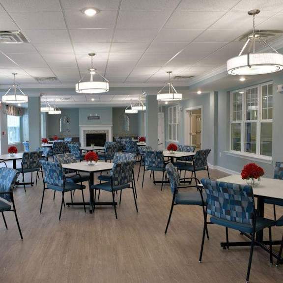 a large room with tables and chairs and a tv on the wall.