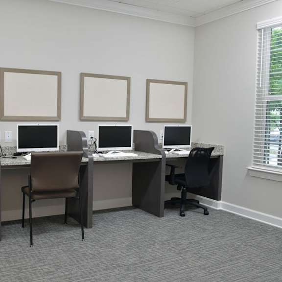 a row of computers are on desks in a room.