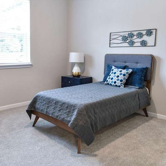 a bedroom with a bed, nightstand, and chair.