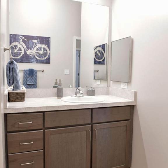 a bathroom with a white counter top and brown cabinets.