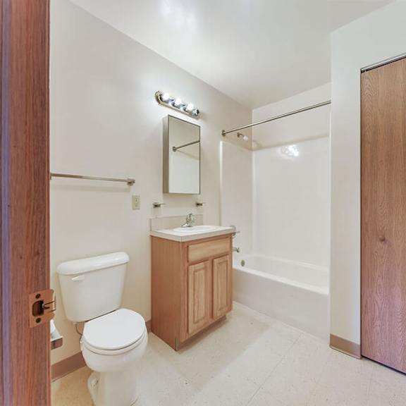 a bathroom with a toilet, sink, and mirror.