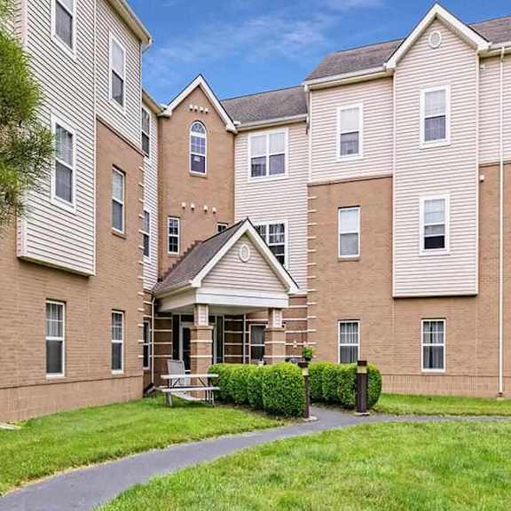 a large apartment complex with a grassy courtyard in front.