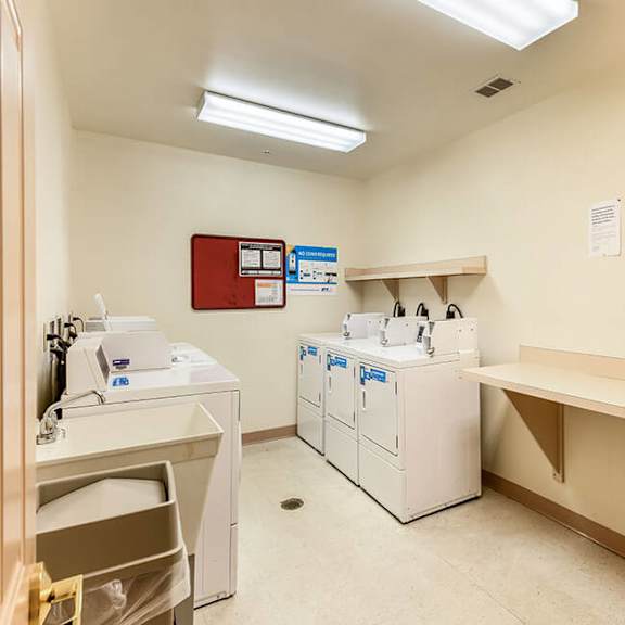 a laundry room with washers and dryers and a bench.