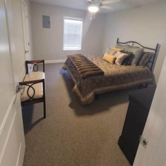 a bedroom with a bed, chair, and window.