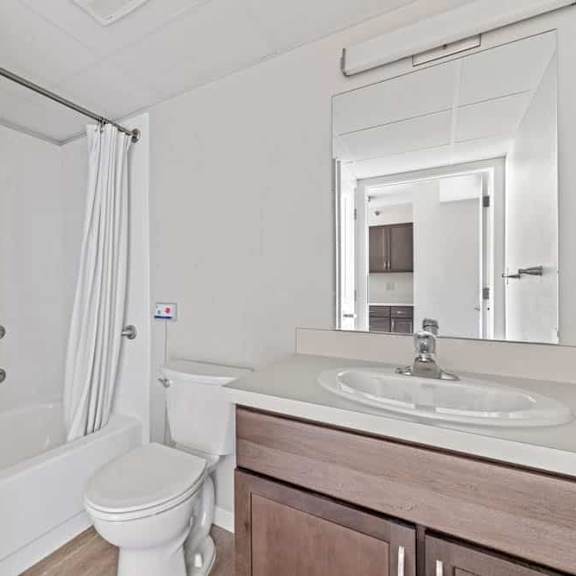 a white bathroom with a toilet, sink, and shower.