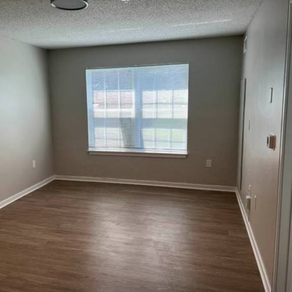 empty room with wooden flooring and a window.