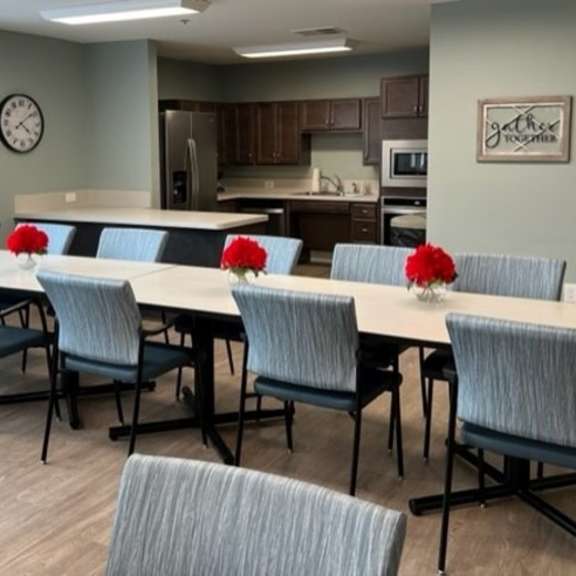 a conference room with a long table and chairs with red flowers on the table.