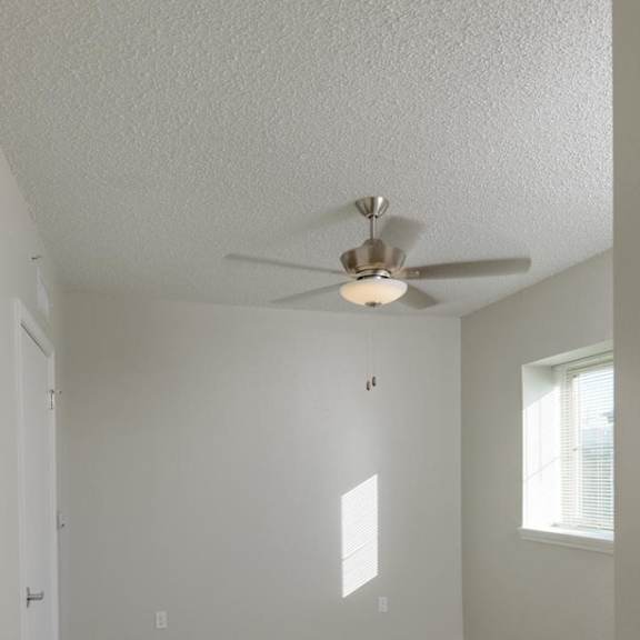 a room with a ceiling fan and carpeted floor.