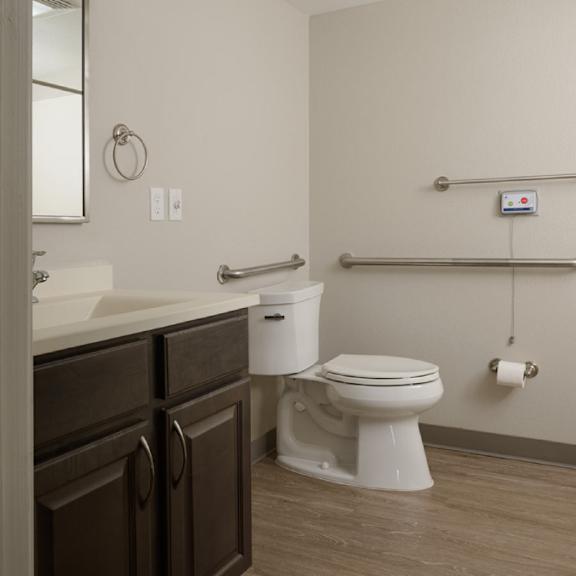 a white toilet sits in a bathroom with brown cabinets.