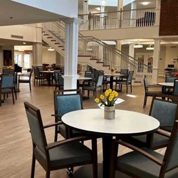 a large room with tables and chairs and a person standing in the distance.