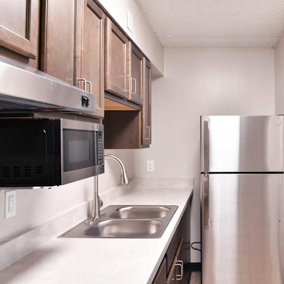 a kitchen with a stainless steel refrigerator, microwave, and sink.