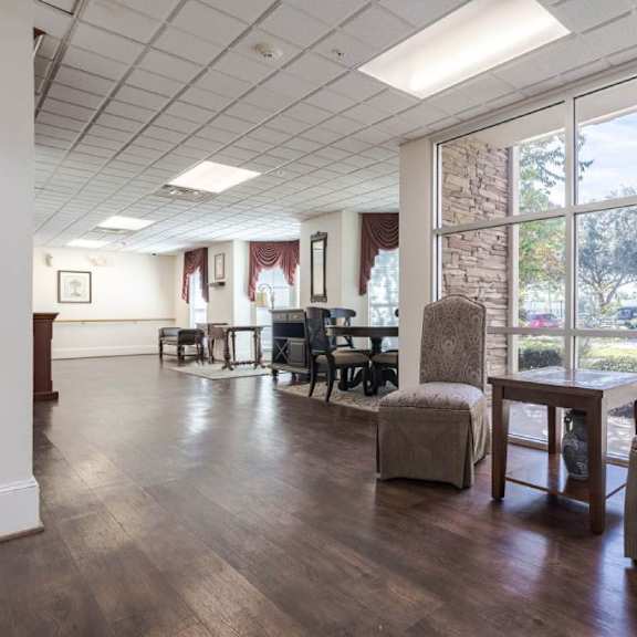 a room with a wooden floor and a large window with a view of trees and a building outside.