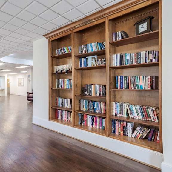 a room with a bookshelf filled with books and two chairs.