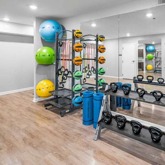 a gym with a mirror, weights, and exercise balls.