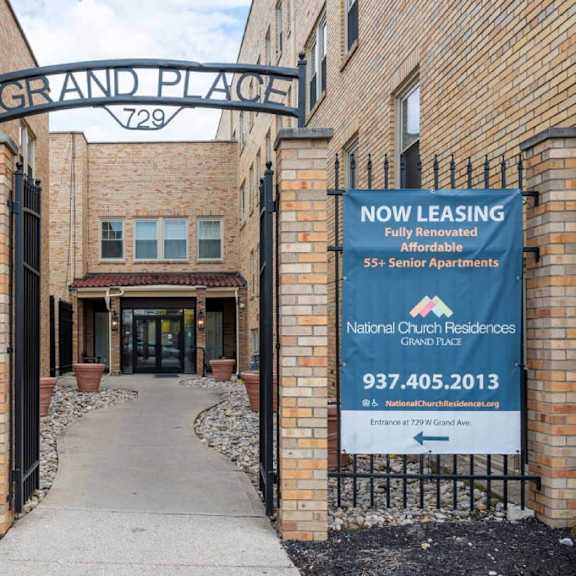 the entrance to grand place apartments with a sign advertising for lease.