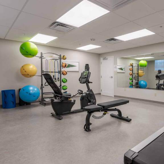 a gym room with a treadmill, exercise balls, and other equipment.