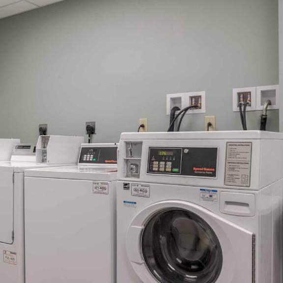 a row of white front load washing machines in a laundry room.