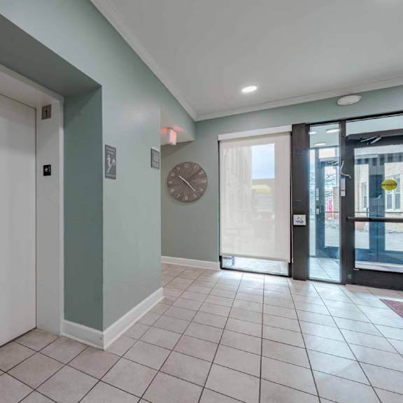 a hallway with a clock on the wall and a door with a glass window.