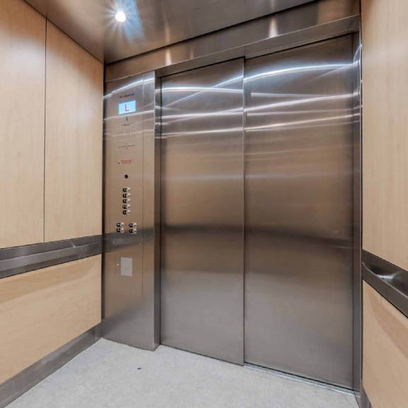 a stainless steel elevator with wood paneling on the sides.