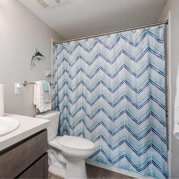 a bathroom with a white toilet and a blue shower curtain.