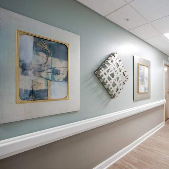 a hallway with artwork on the walls and a wooden floor.