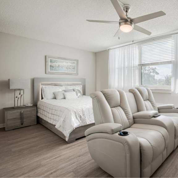a bedroom with a bed, a couch, and a ceiling fan.