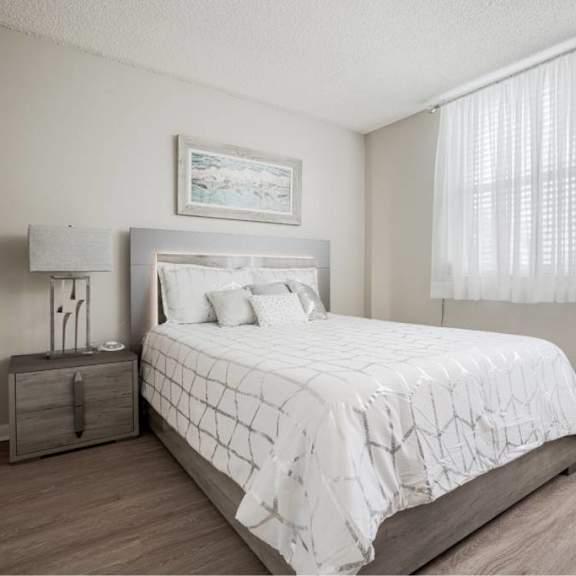 a bedroom with a large bed and a window with white curtains.