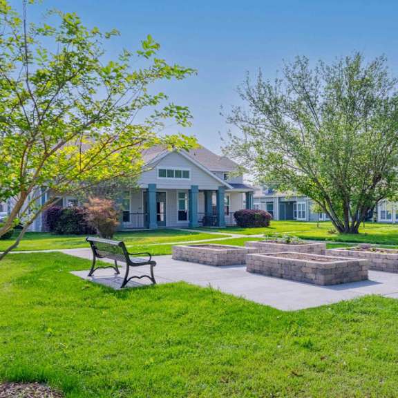 a park with benches and a fire pit in front of a house.