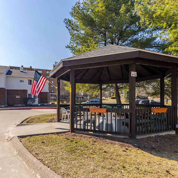 a gazebo with a flag on a building in the background.