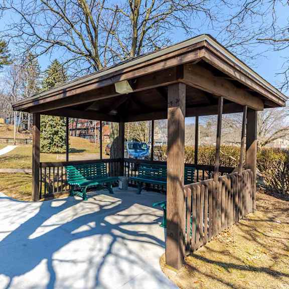 a wooden pavilion with a green bench is surrounded by a wooden fence.