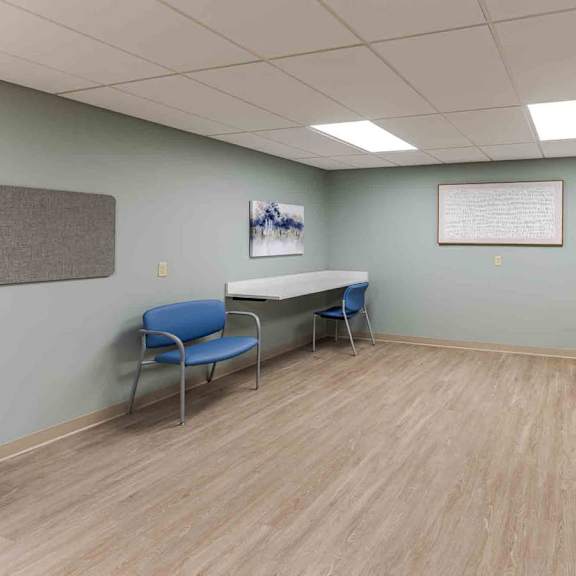 a medical room with a washing machine and a blue chair.